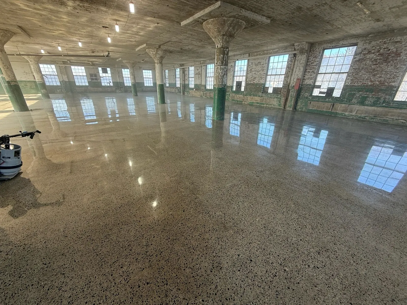 Polished concrete floor reflecting tall windows in a converted mill
