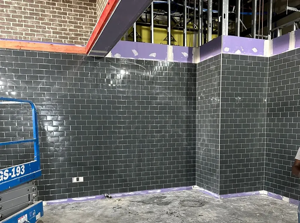 Dark gray subway tile wall mid-install