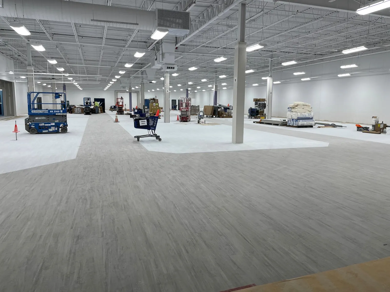 Wide retail floor mid-install with lifts and pallets on site